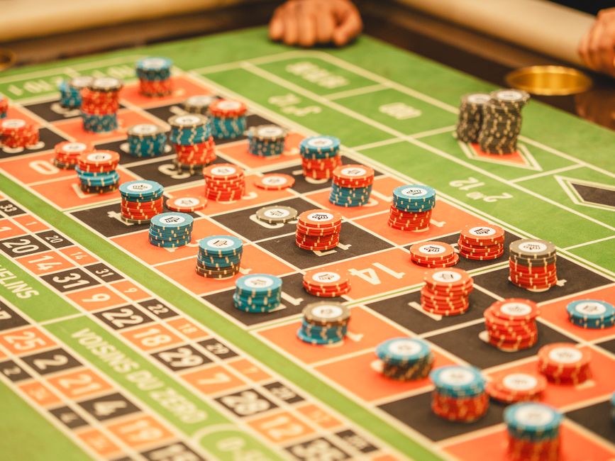 Colorful roulette table with stacks of casino chips in a lively atmosphere.